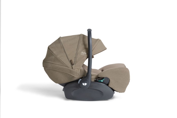 Fotelik samochodowy Joie i-Level Pro w kolorze sandstone, widziany z boku w pozycji leżącej. Rączka fotelika jest uniesiona, a daszek jest rozłożony. Widoczny jest mechanizm regulacji pochylenia.
