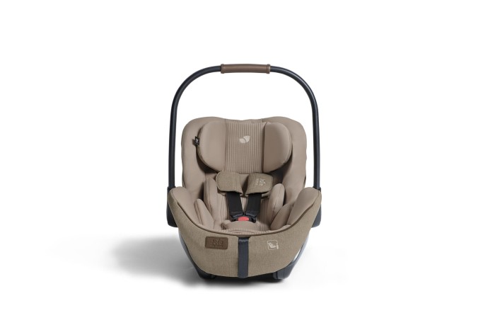 Fotelik samochodowy Joie i-Level Pro w kolorze sandstone, widziany od przodu. Daszek jest złożony, a rączka jest podniesiona. Zdjęcie eksponuje zagłówek Tri-Protect™ oraz pasy bezpieczeństwa.