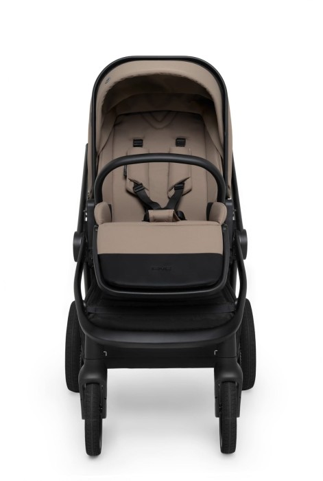 Frontalny widok wózka Muuvo FIVE Mokka w wersji spacerowej. Siedzisko w beżowo-brązowym kolorze z czarną barierką i pasami bezpieczeństwa. Wózek łączy stylowy design z dbałością o komfort i bezpieczeństwo dziecka.