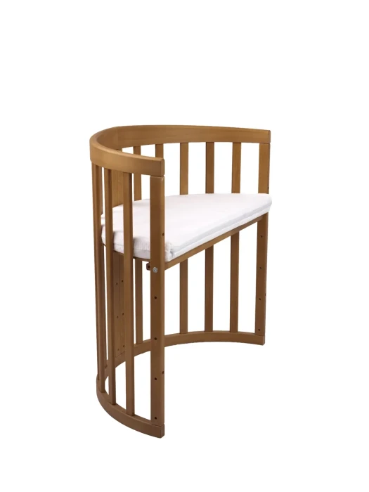 Łóżeczko 7w1 Waldin Owal-V Vintage z otwartym bokiem, przystosowane do funkcji dostawki do łóżka rodziców. Widoczne gumowane kółka w beżowym kolorze.